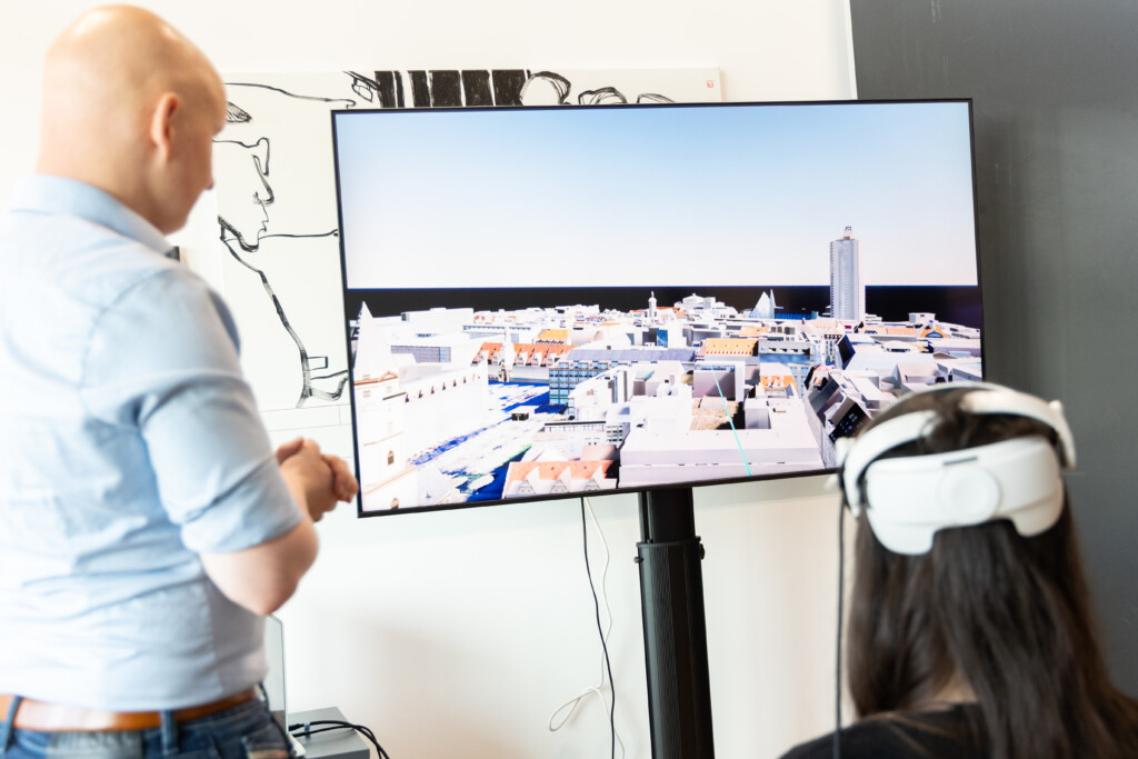 Person trägt eine VR-Brille und blickt in Richtung eines Bildschirms